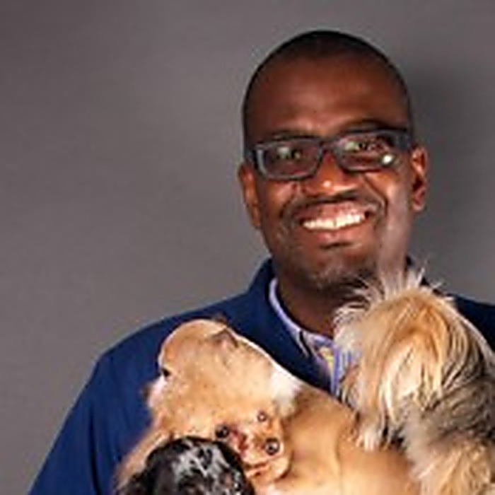Dr. Gregory A. Hardy, DVM, lead veterinarian at Best Friends Pet Hospital, holding three small dogs